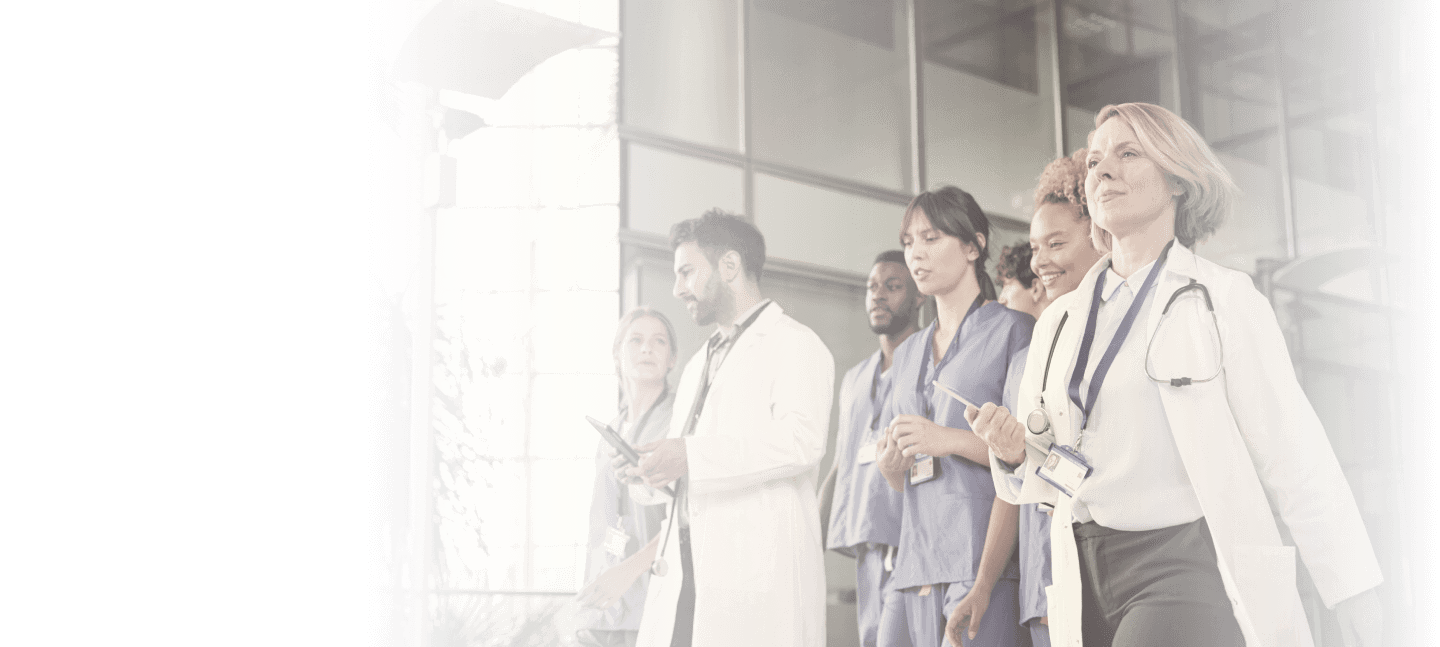 A group of physicians and nurses walking outside a hospital