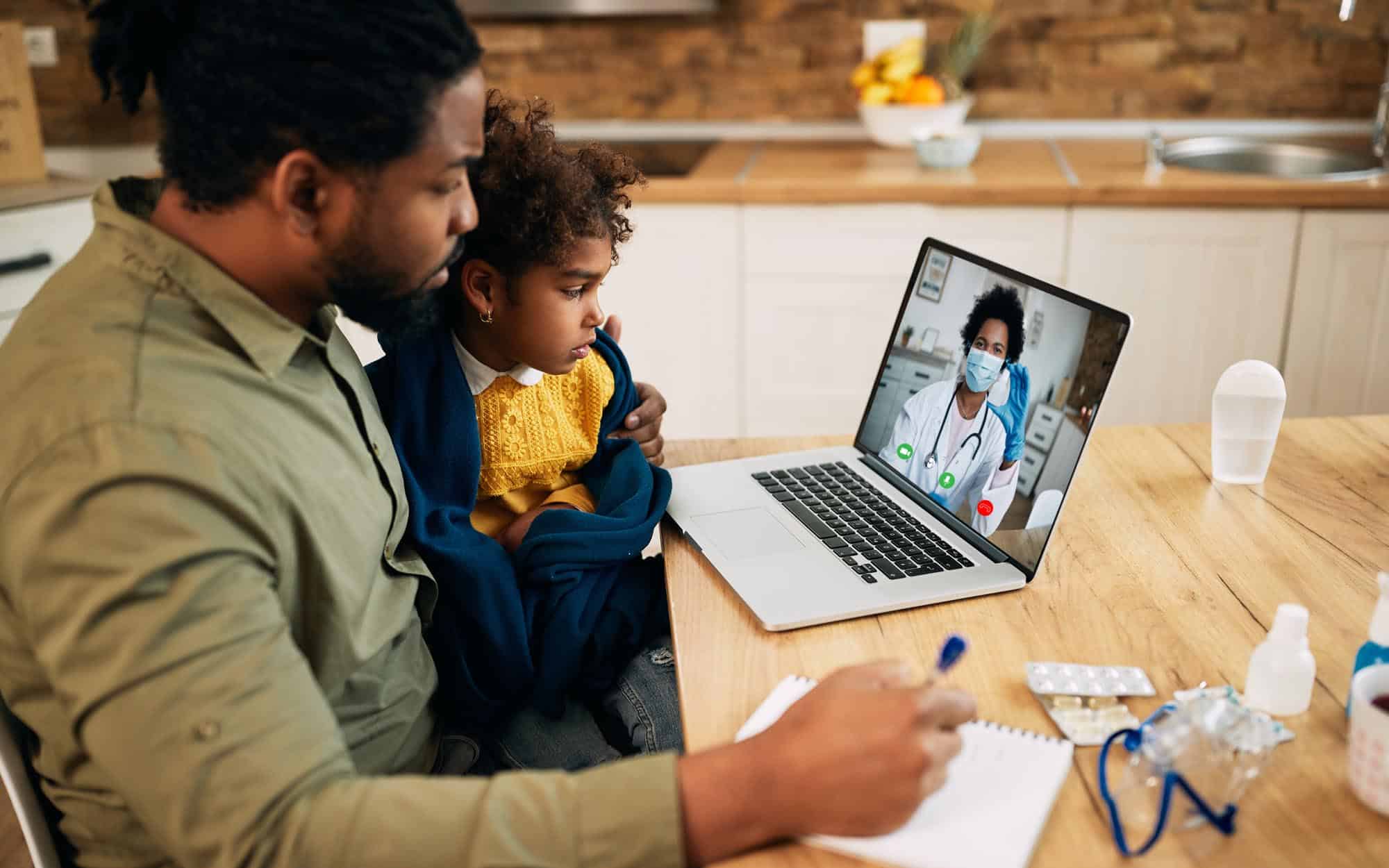 father and daughter having video call with family doctor